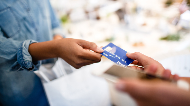 A Visa card being handed to a salesperson in a retail store